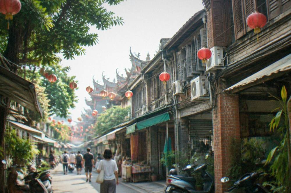 Pedestrians walking down a narrow old lane between small shops in daylight