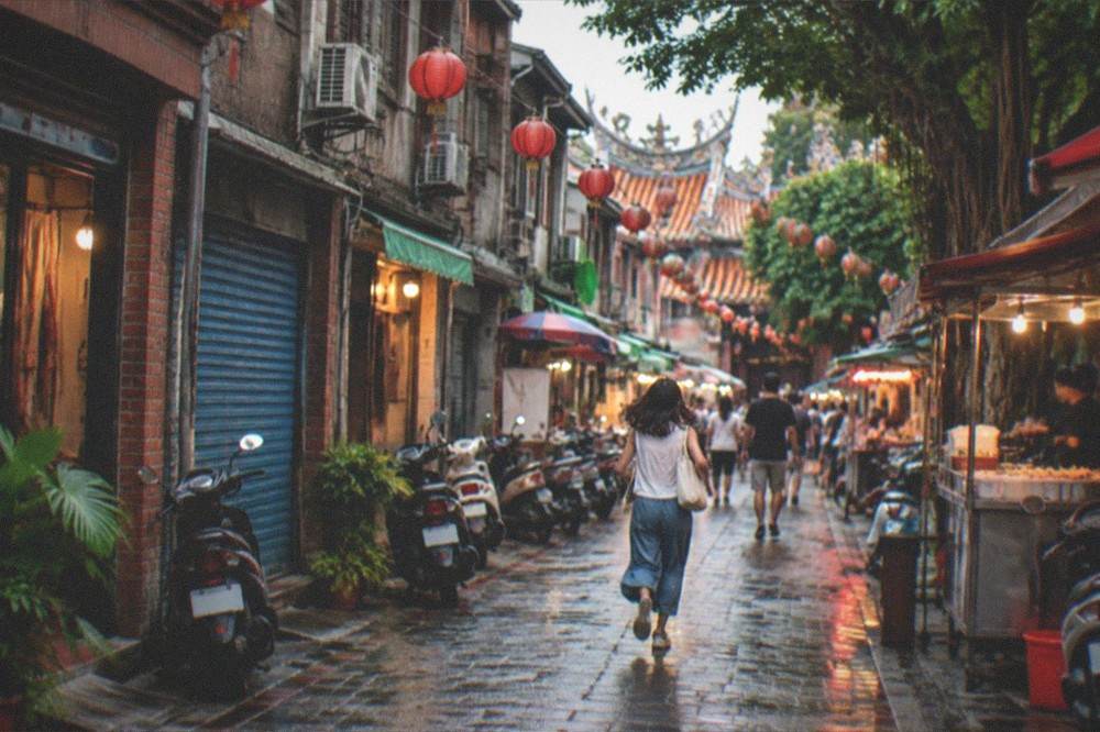 Crowds and food stalls at a Taiwanese night market lit in the evening