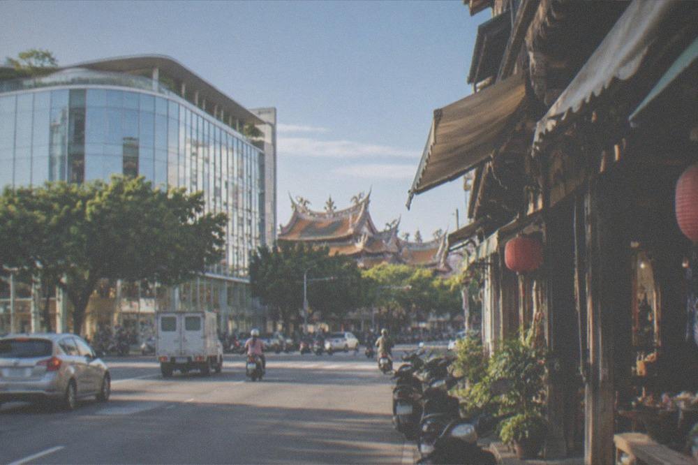 A narrow old street storefront with a carved timber shopfront and hanging cloth awnings, any boards angled away and out of focus