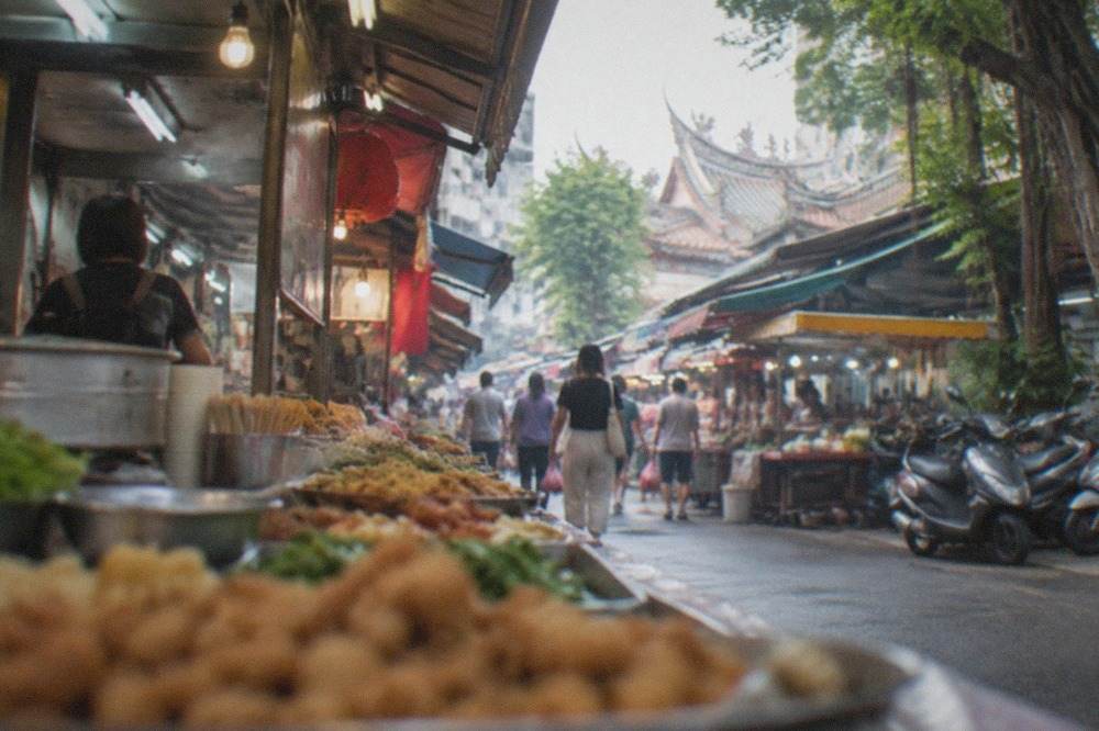 A covered night market aisle in Tainan with food stalls and shoppers under ceiling lights