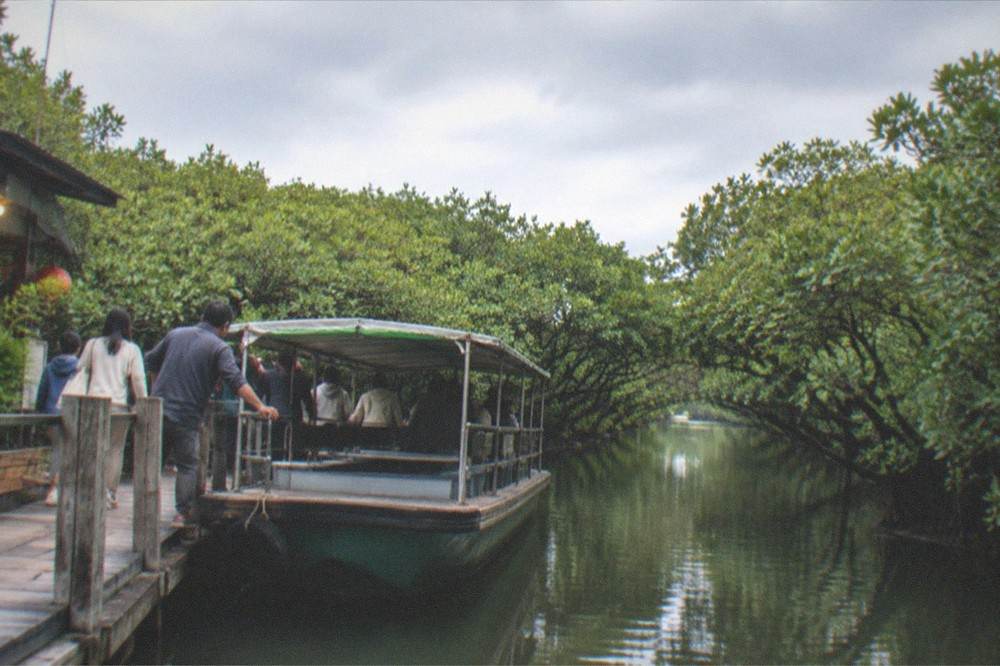 Families boarding a flat covered boat at a wooden pier while a crew member holds the rail steady