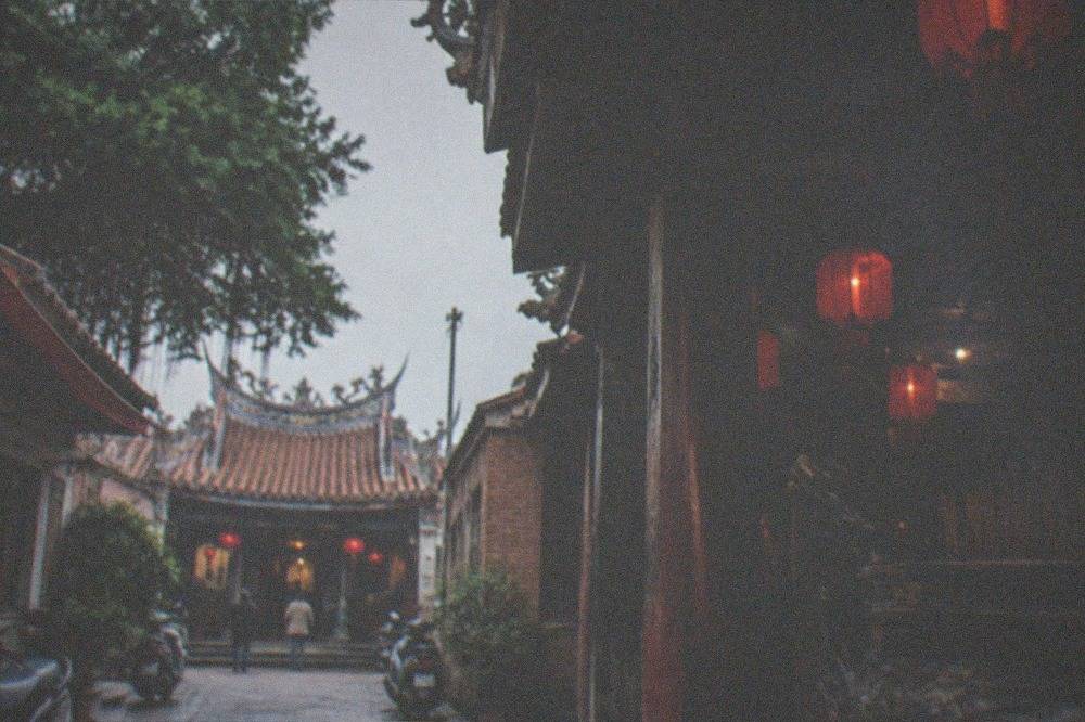 Narrow old lane in Tainan with low brick buildings, wooden shutters and a small temple doorway at the end