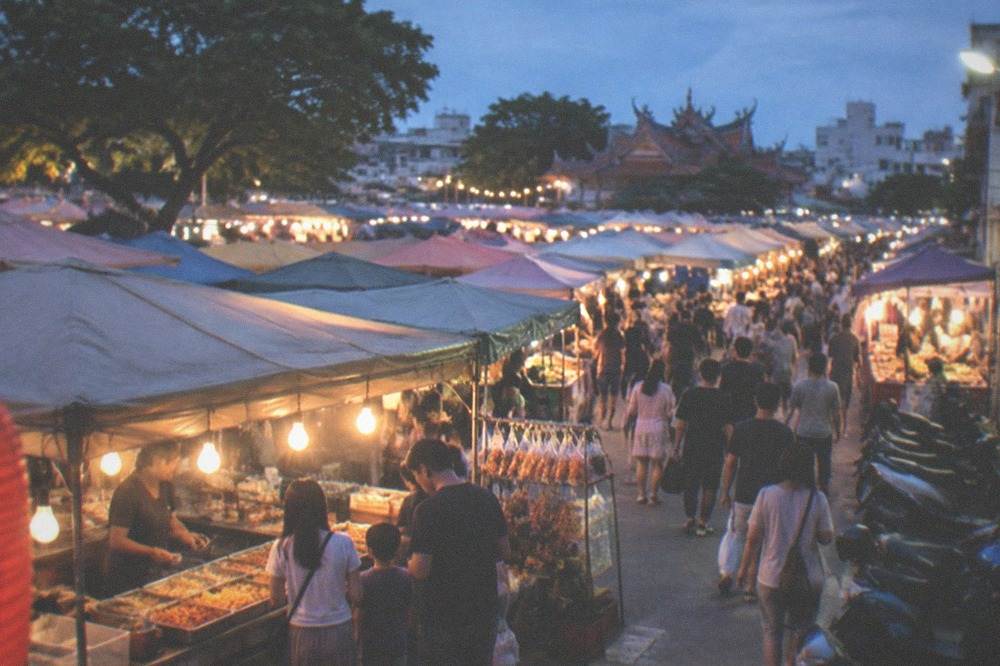 A family ordering food at a market stall counter with hanging menu signs