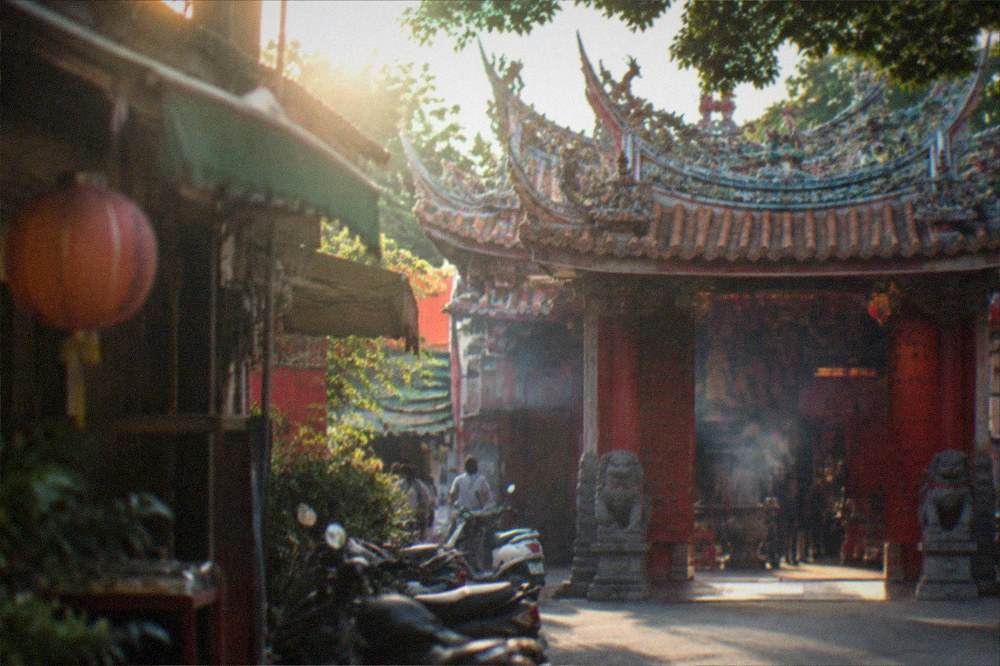 An ornate temple gateway with red doors, stone lions and calligraphy plaques in Tainan