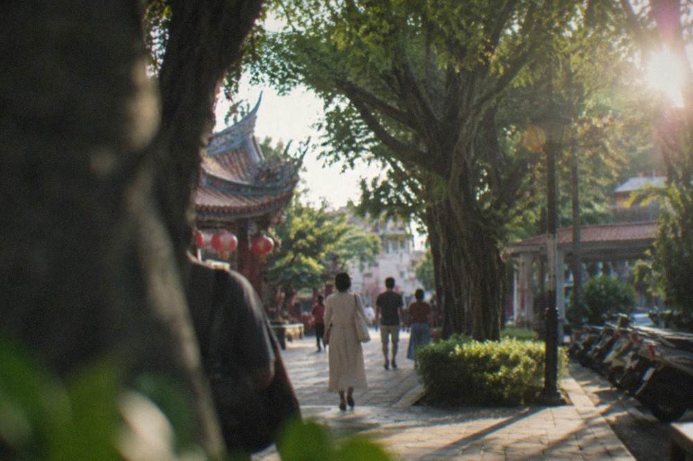 Tree-lined walking paths in a Tainan park with people strolling in the shade