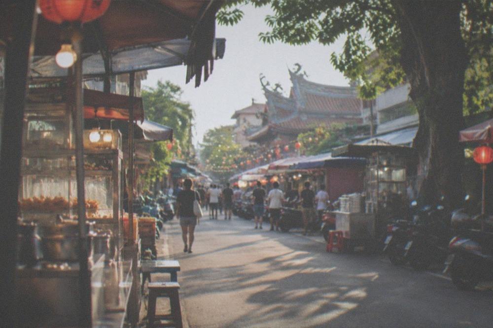 A busy Taiwanese night market aisle with food stalls and string lights at night