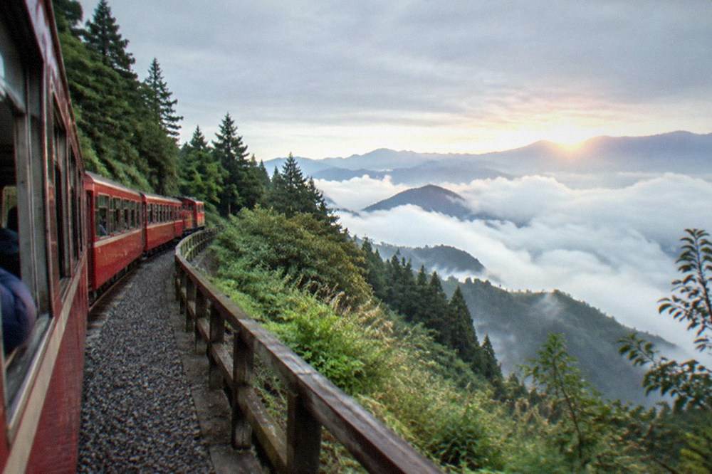 Sunrise light breaking over a sea of clouds above forested mountain peaks
