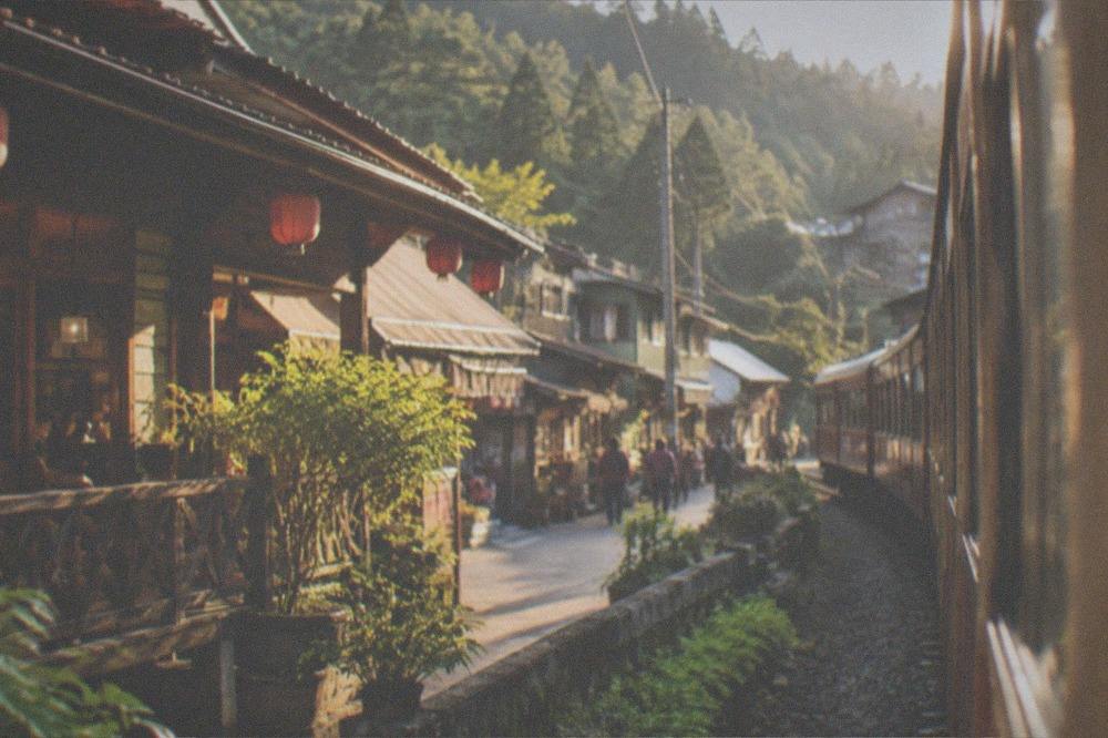 A small mountain village street with wooden buildings and forest slopes behind