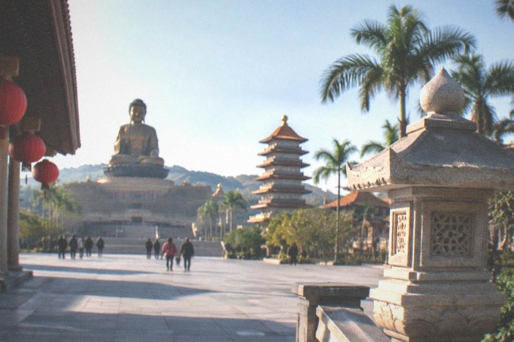 A wide courtyard at a monastery with palm trees and clear sky in warm daylight