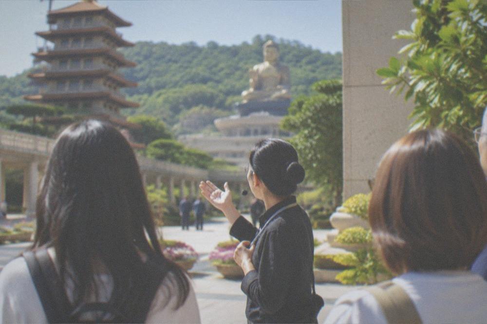 A guide speaking to a small group of visitors in a temple courtyard