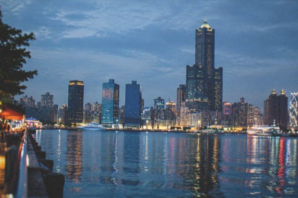 The illuminated harbor skyline of Kaohsiung reflected in the water at night