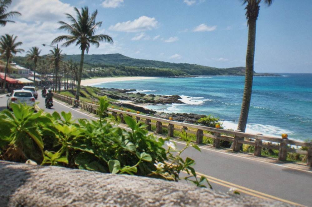 Coastal road with palm trees and a blue sea horizon on the Kenting peninsula in southern Taiwan