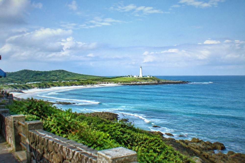 White lighthouse and green lawn at the Eluanbi lighthouse park on the southern tip of Taiwan