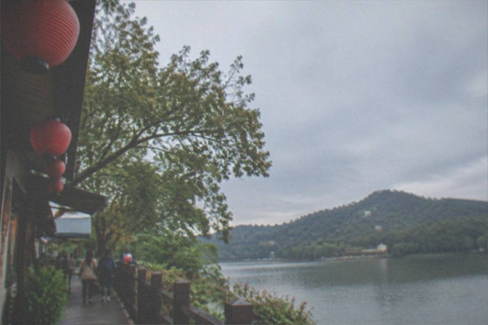 A calm lake surrounded by trees and hills at late afternoon