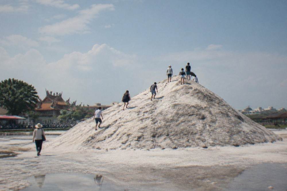 Visitors walking up the white slope of the salt mountain under a hot sun