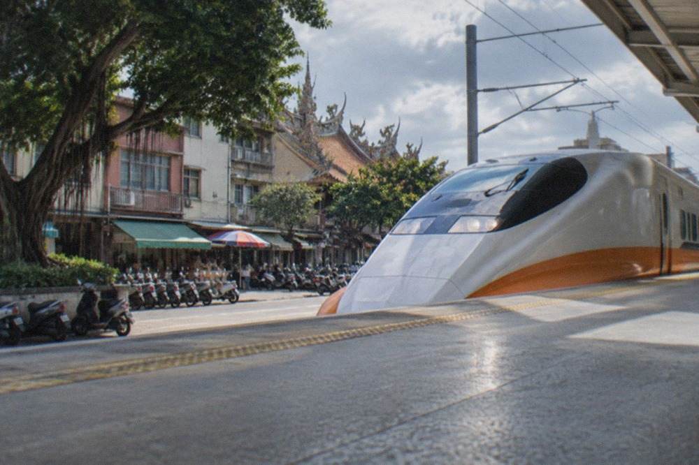 A high speed rail train standing at a Taiwan station platform under a bright sky