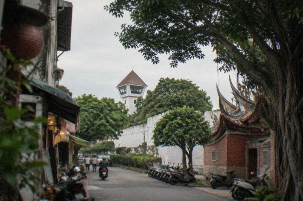 The white walls and observation tower of Anping Old Fort seen through trees