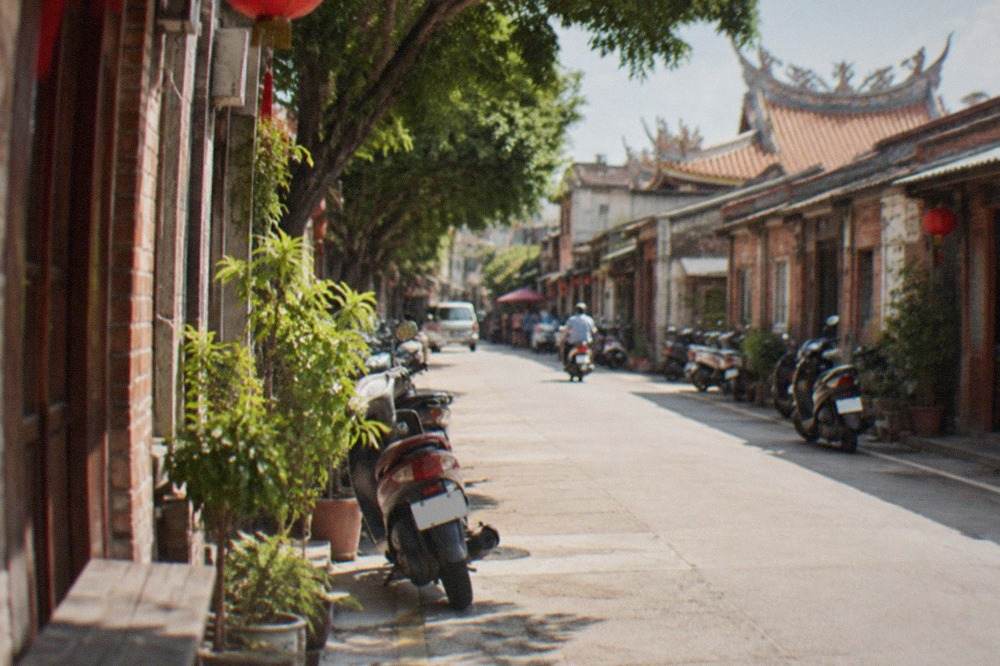 A historic Taiwanese old street with low brick shopfronts and a narrow lane in warm afternoon light
