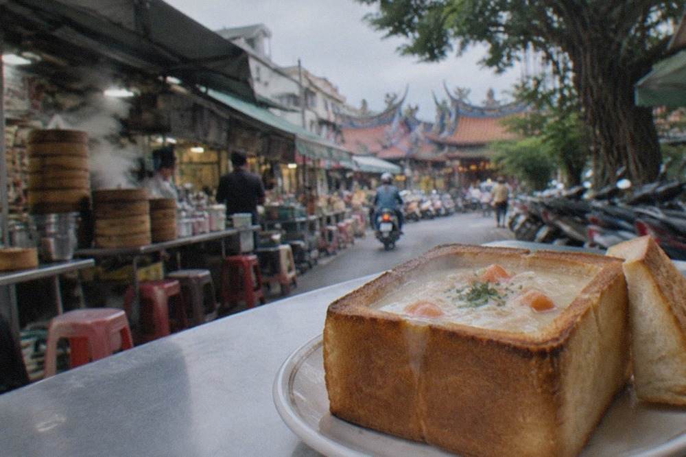 A golden toasted bread box filled with creamy stew, served on a plate in a Tainan eatery