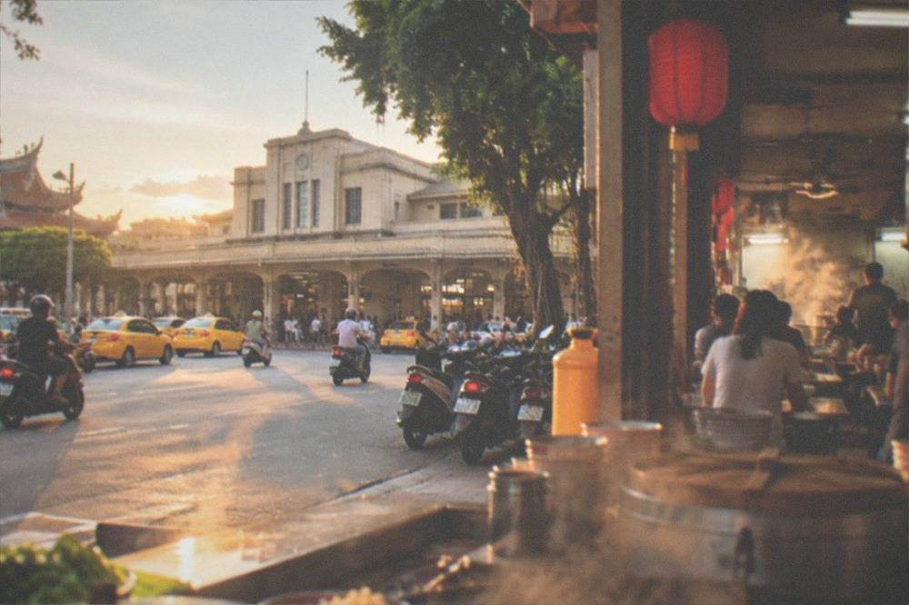 A busy Tainan snack shop interior with steam rising from cooking stations and customers seated at small tables