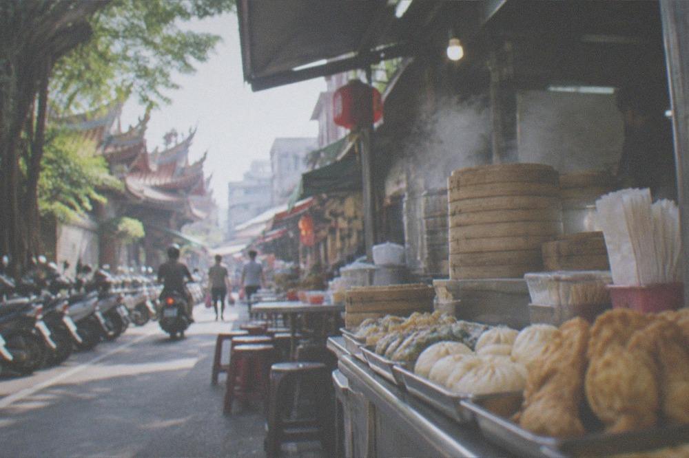 A Tainan snack shop counter with trays of freshly made snacks and a stack of paper bags, the wall board cropped out of frame