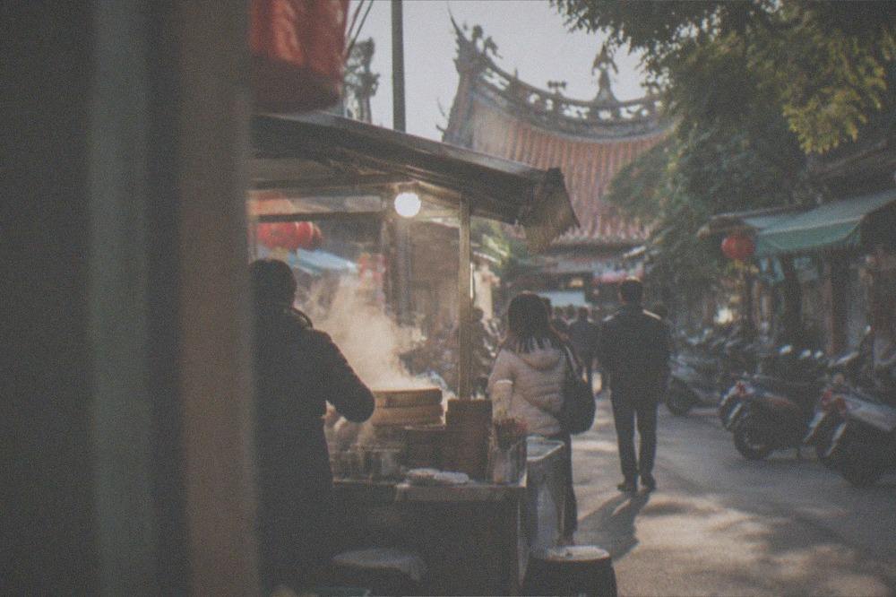 A night market stall steaming in cool evening air with customers in light jackets