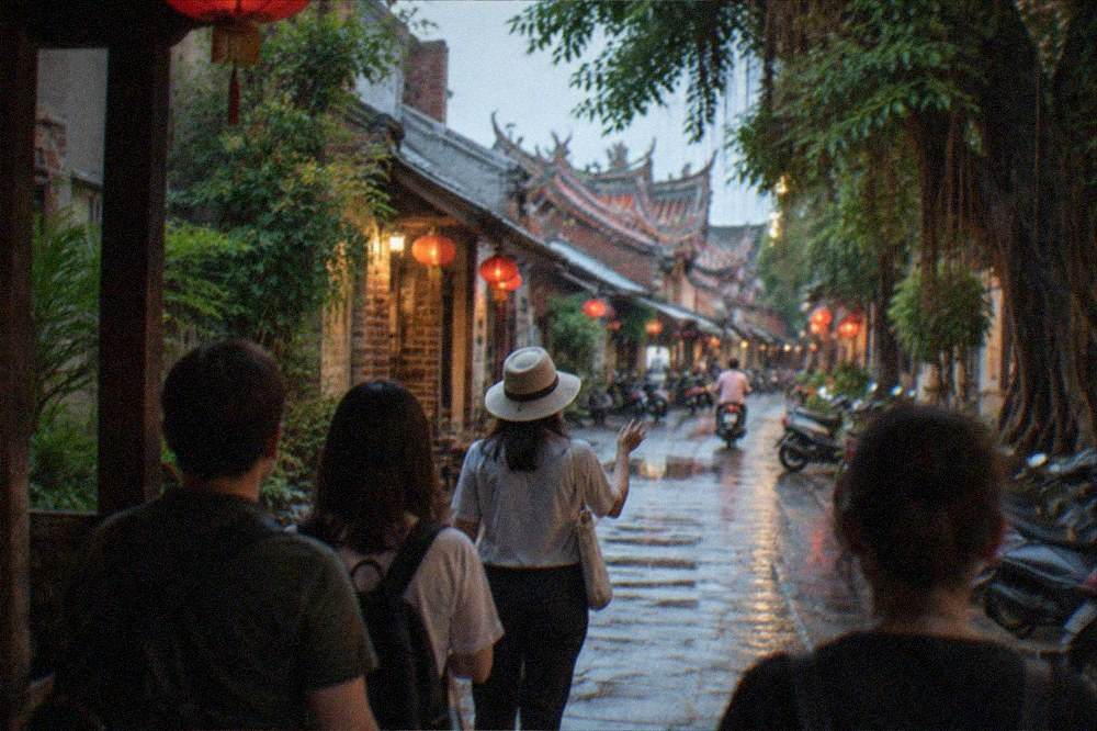 A guide leading a small group of visitors along a lantern-lit old street in the evening