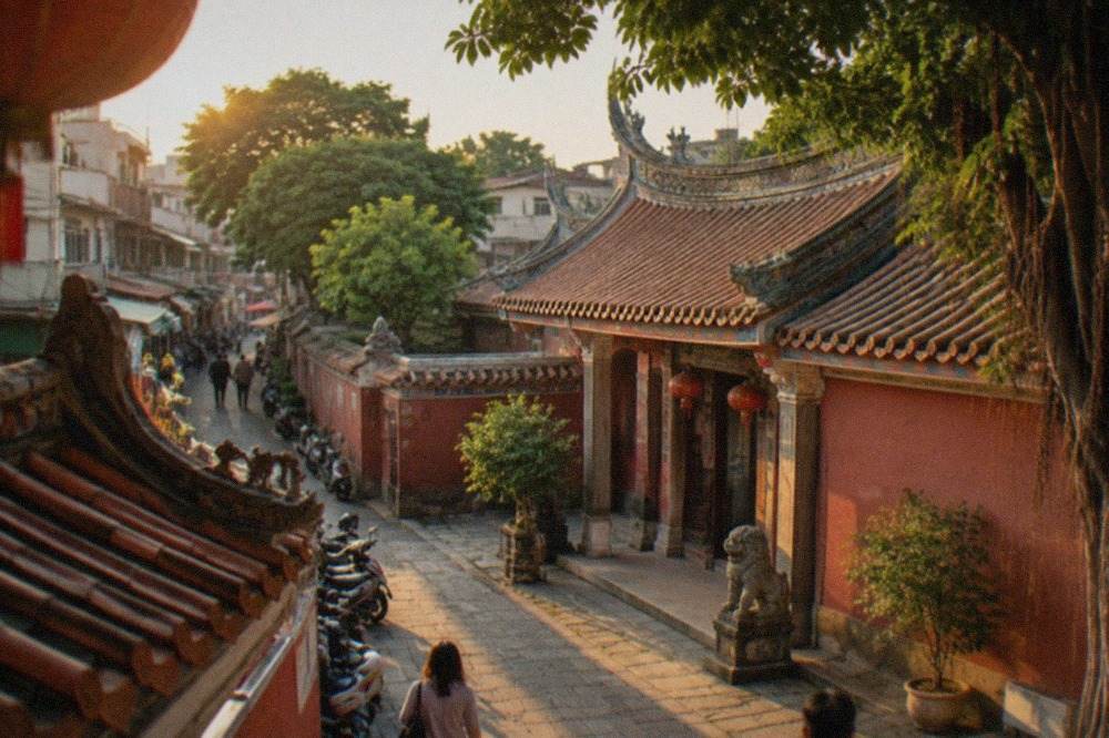 A historic Tainan temple courtyard with red walls and traditional tiled roofs under a clear sky
