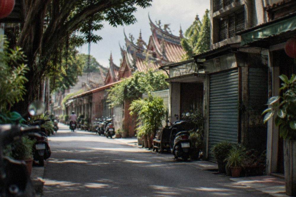 A quiet old Tainan street with low traditional buildings, shutters and potted plants