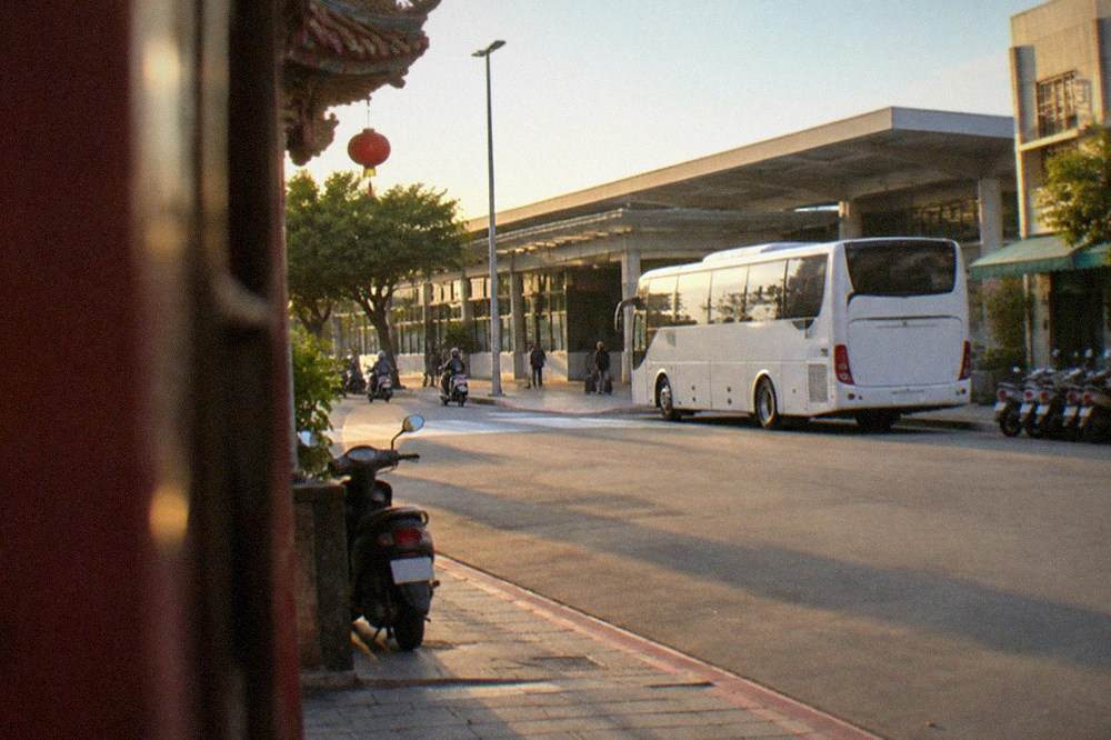 A white express bus parked outside a modern high speed rail station under a blue sky