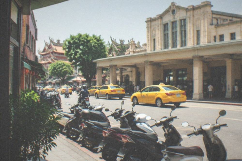 Scooters parked in a row on a Tainan street next to old brick buildings