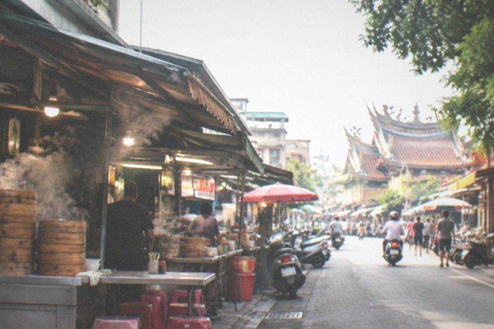 A narrow Tainan food street with small shop fronts and hanging signs