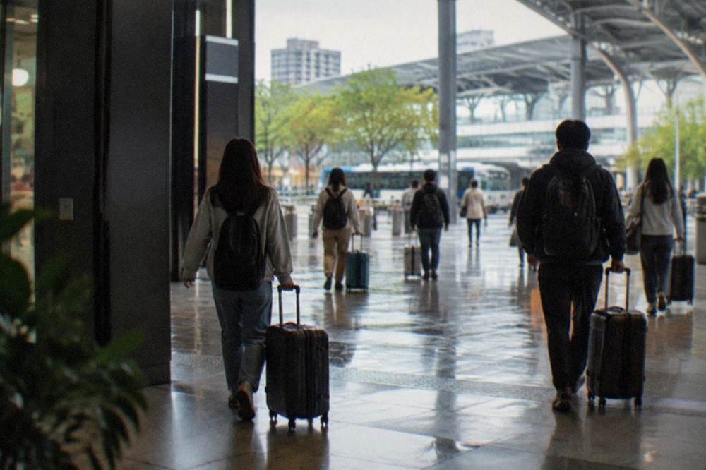 Travelers with luggage walking through a modern rail station concourse