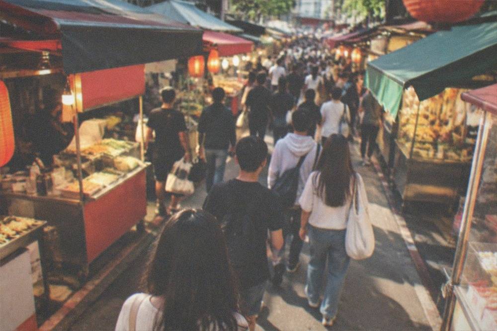 Crowded night market aisle lit by stall lights in the evening