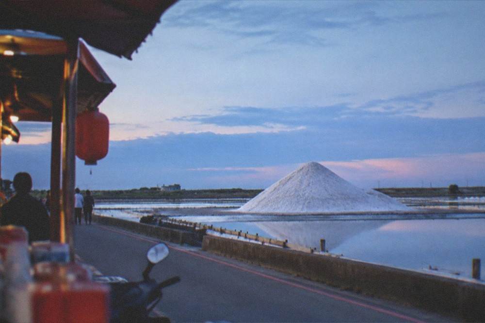 White salt mound rising above flat coastal fields at Qigu