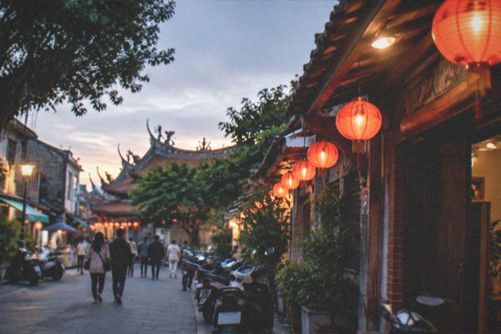 A lantern-lit historic street in Tainan at dusk with visitors walking