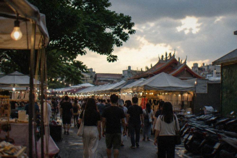 Crowded aisles of a Tainan night market lit by strings of bare bulbs