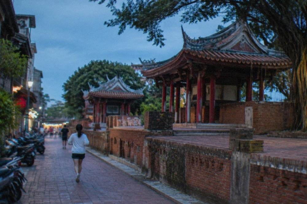 Old brick rampart walls of a historic Tainan fort under a blue sky with banyan trees nearby