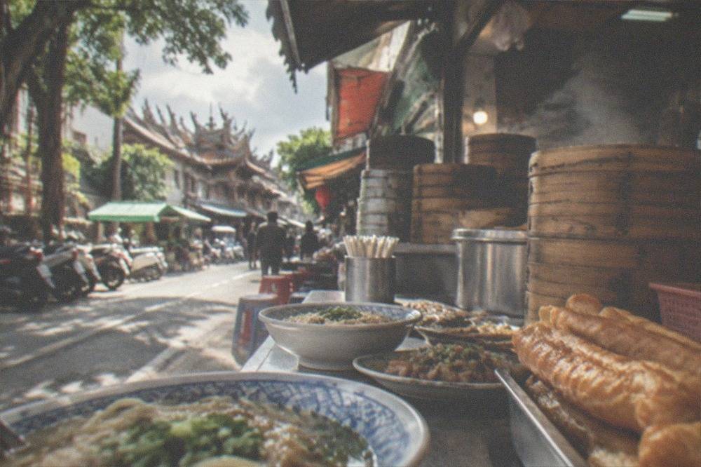 Small bowls of Taiwanese street food including noodles and fried bread on a market counter