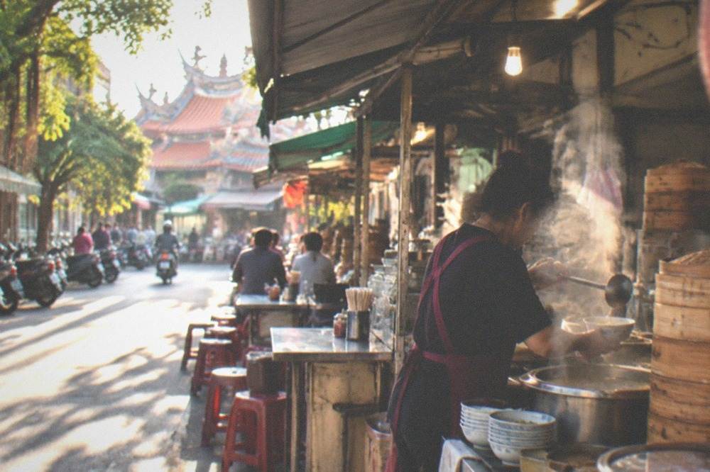 A cook ladling broth into a bowl at a small Tainan breakfast counter