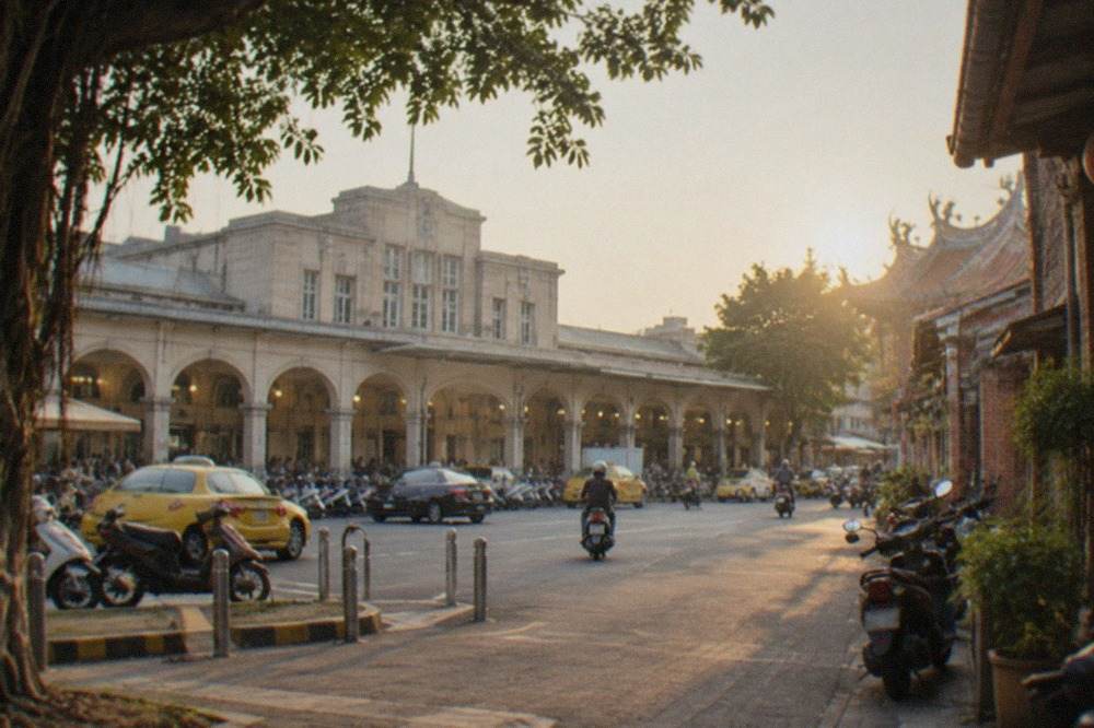 A narrow Tainan old street at golden hour with low brick buildings and parked scooters