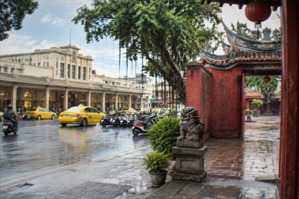 A stone temple courtyard with red walls and open gates in afternoon light