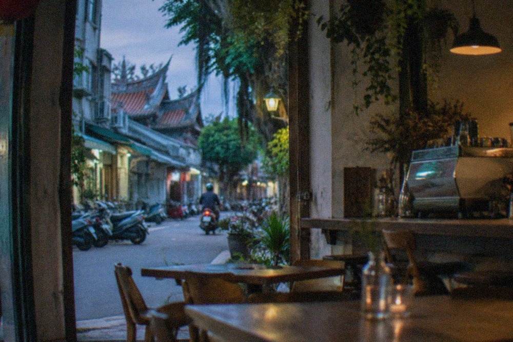 A quiet Tainan cafe interior with wooden tables, hanging plants and an espresso machine on the counter