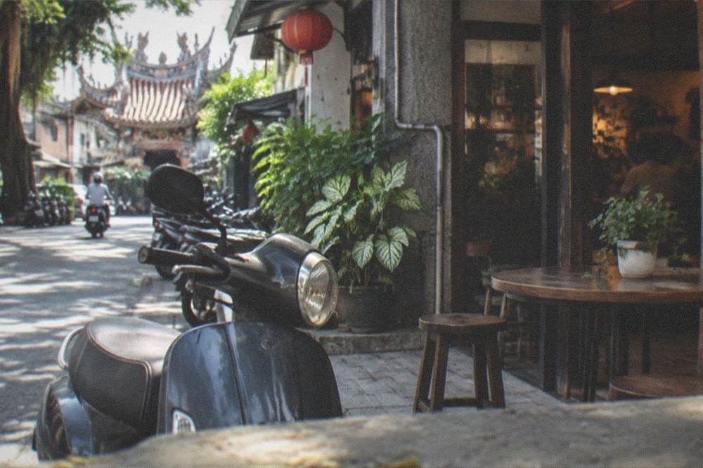A scooter parked outside a small Tainan cafe with a chalkboard menu by the door