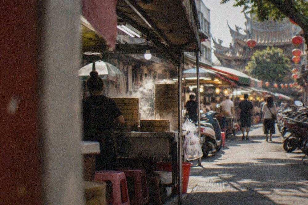 A busy Tainan night market aisle at dusk with food stalls and hanging lights