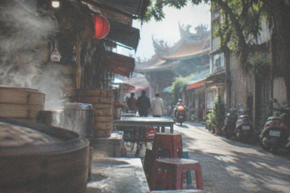 A narrow old street in Tainan with small food stalls and scooters parked along the walls