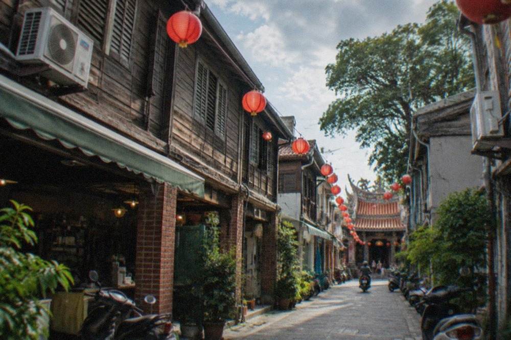 A narrow old Tainan street with low brick buildings and a small temple doorway at the end