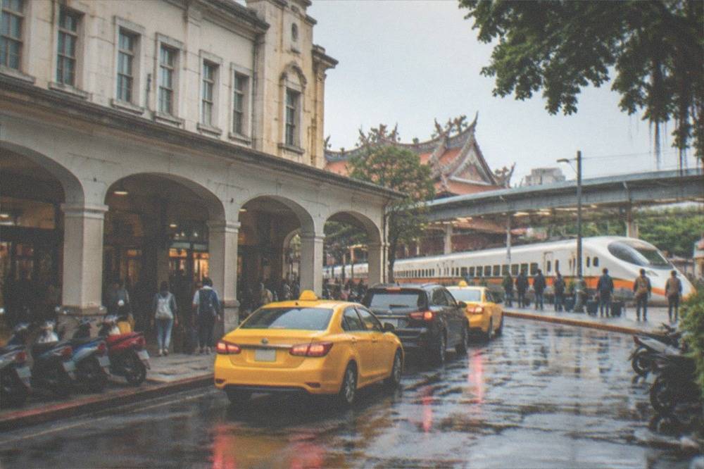A high speed train at a Taiwan station platform with passengers waiting with luggage