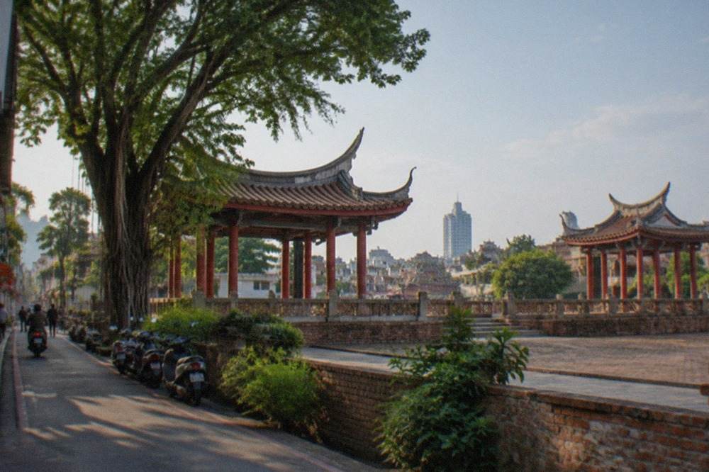 Aerial view of Tainan rooftops with temple roofs and a modern tower in the distance