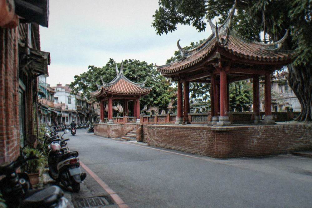 A narrow old street in Tainan with low brick buildings and scooters parked along the side